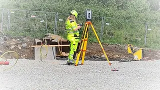 Person som utfører oppmålingsarbeid, også kalt landmåling eller geomatikk, på en byggeplass. 